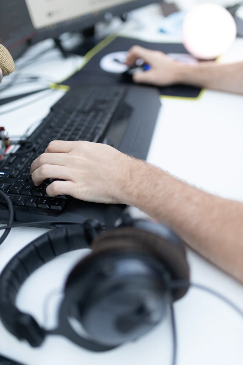 Mains sur le clavier pendant un montage vidéo, casque audio au premier plan