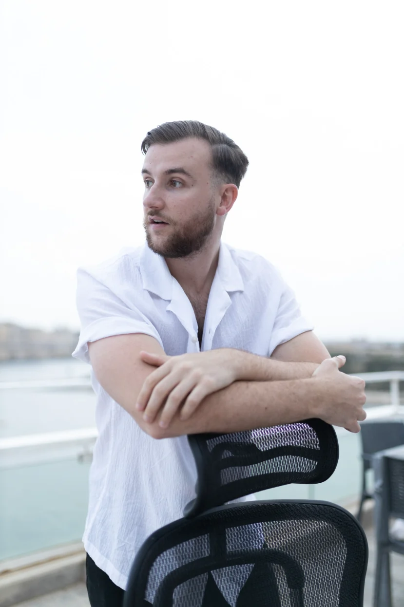 Théo Bayoux accoudé au dossier de sa chaise de bureau, regard de côté