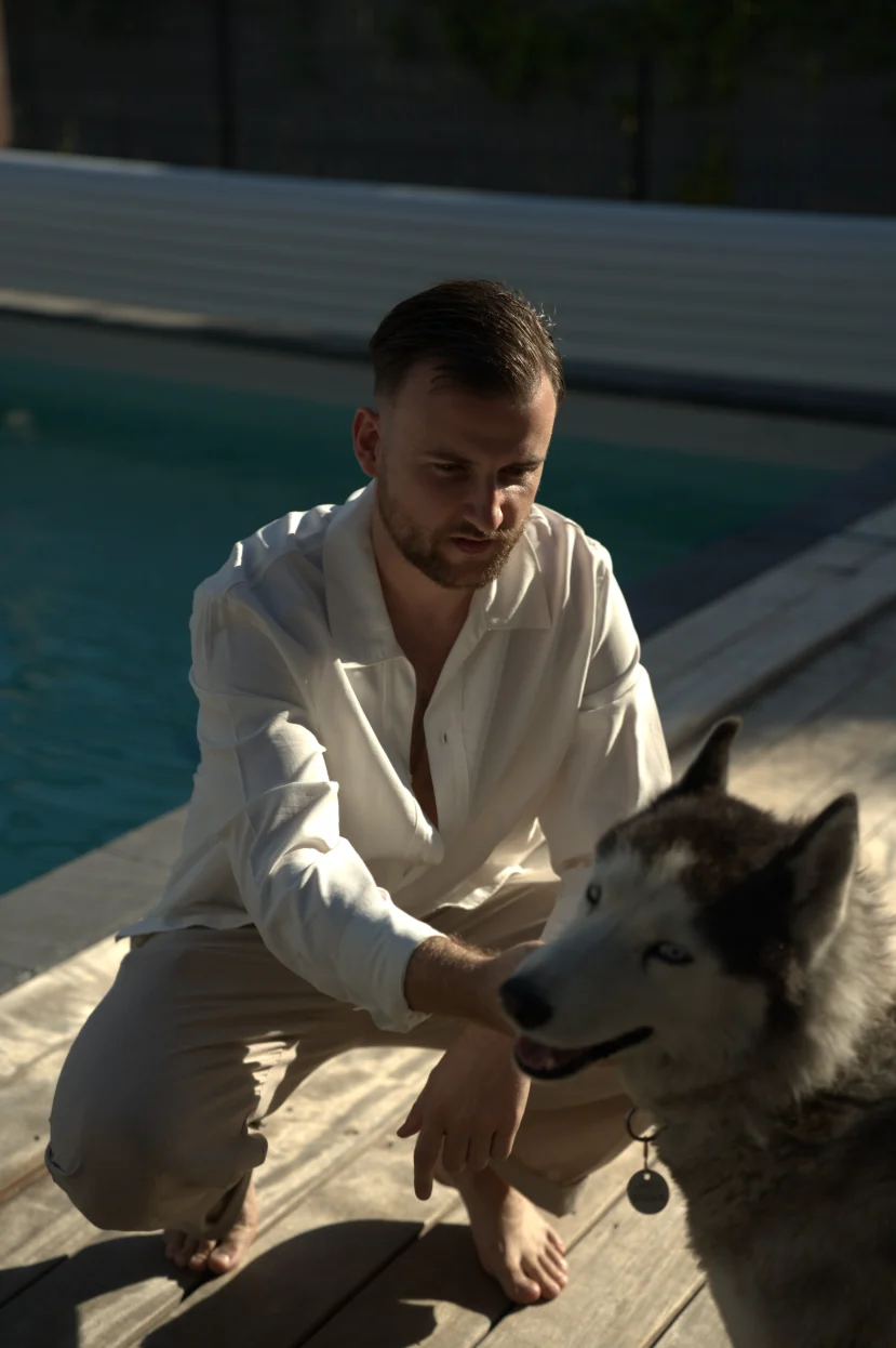 Théo Bayoux accroupi au bord de la piscine avec son husky