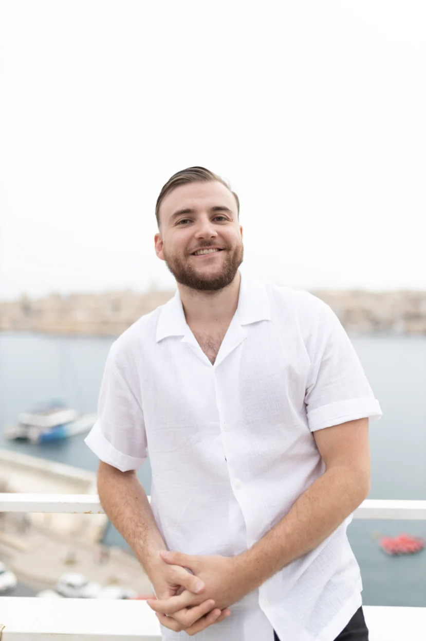 Théo Bayoux souriant face à l'objectif, mains jointes, la mer derrière lui