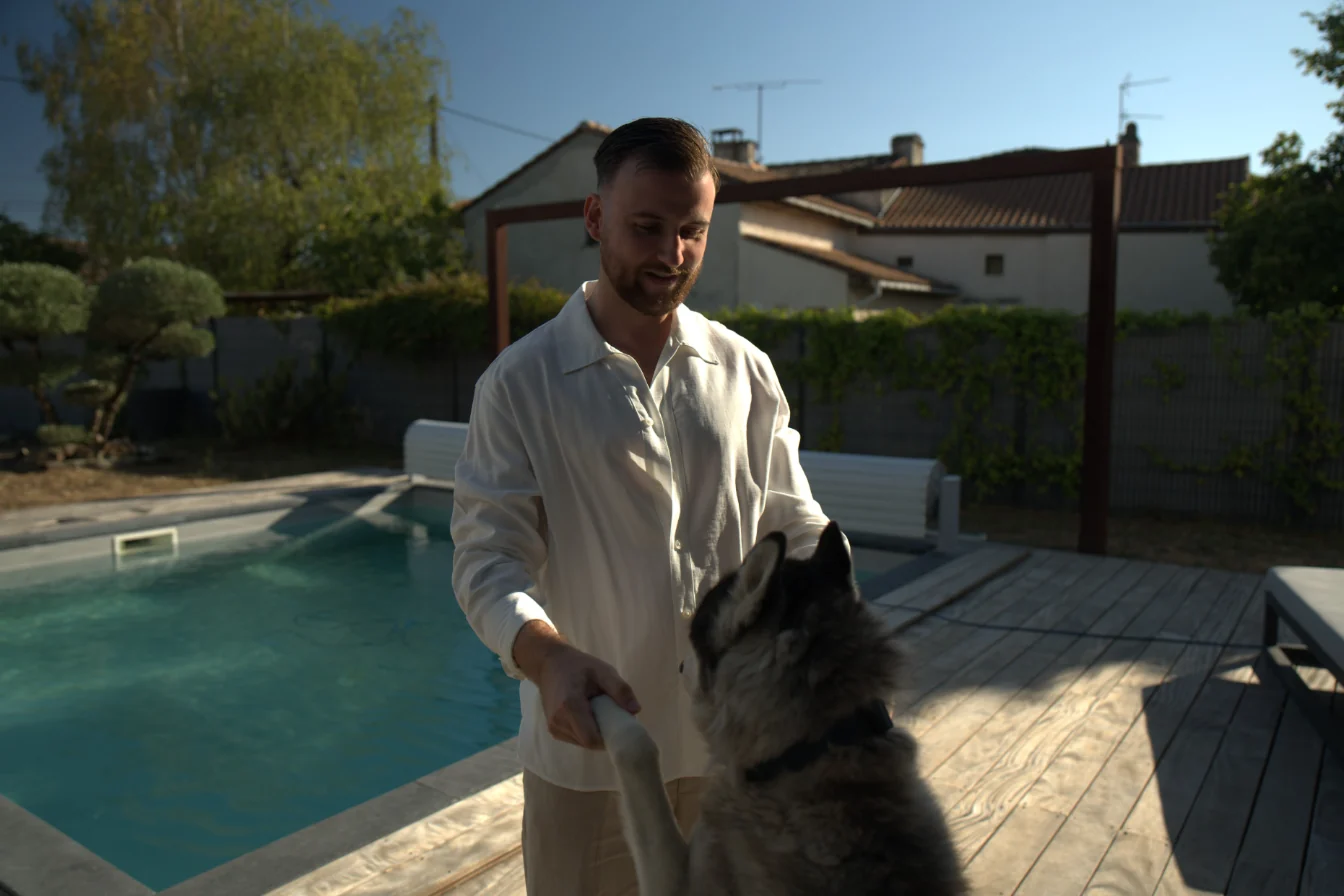 Théo Bayoux joue avec son husky au bord de la piscine