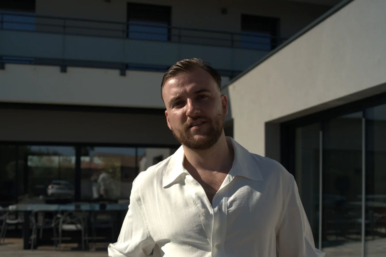 Théo Bayoux devant une maison moderne, en plein soleil