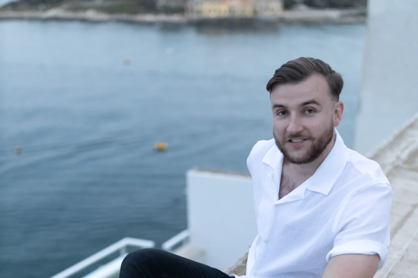 Théo Bayoux souriant, assis au-dessus de la mer