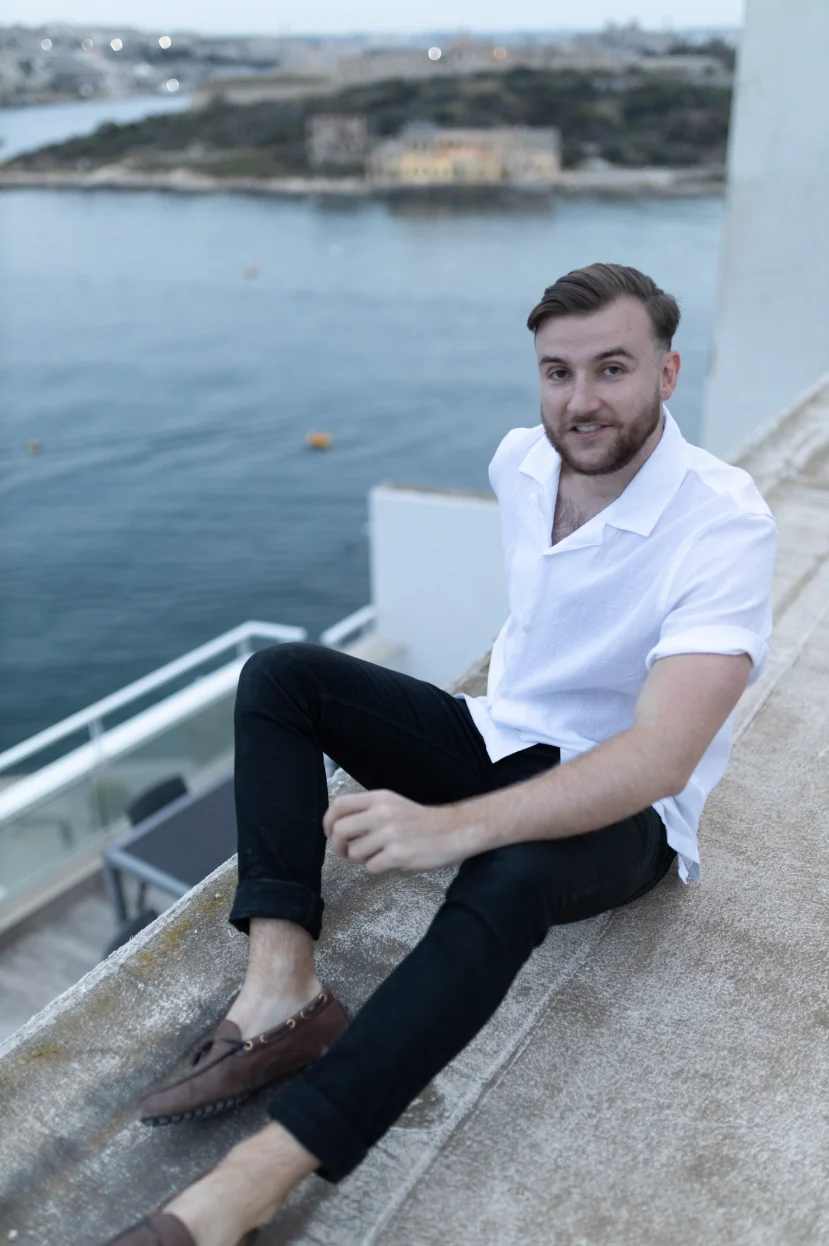 Théo Bayoux assis sur un muret au-dessus de la mer