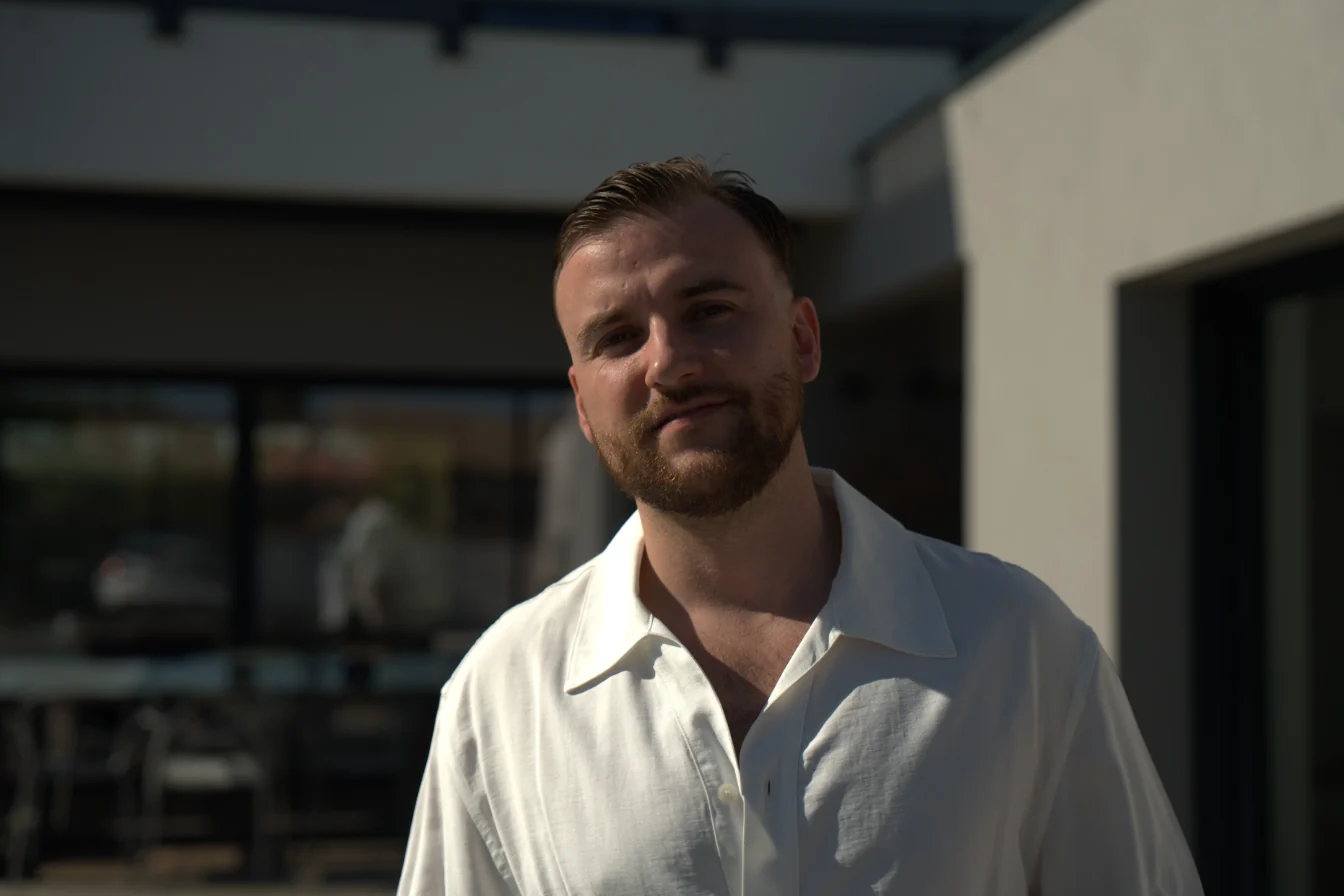 Portrait de Théo Bayoux en chemise blanche devant une maison moderne