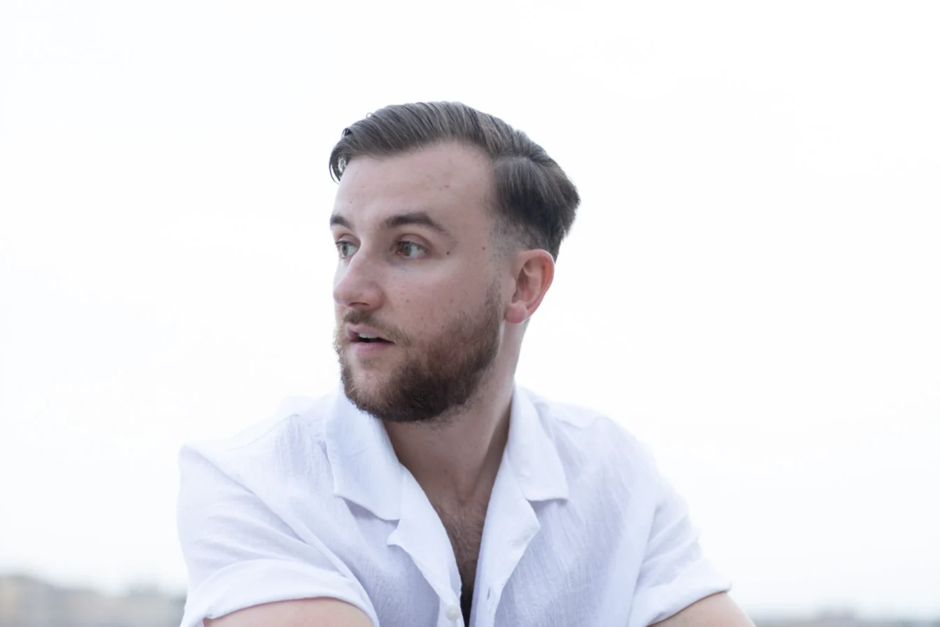 Théo Bayoux regarde sur le côté, en chemise blanche