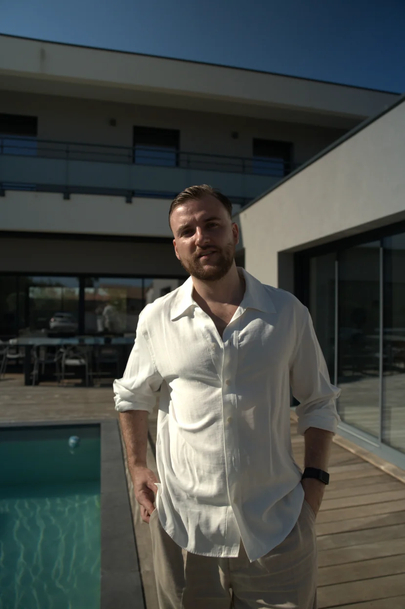 Théo Bayoux debout au bord d'une piscine devant une maison moderne