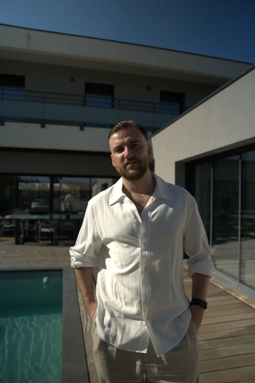 Théo Bayoux, mains dans les poches, devant une maison moderne